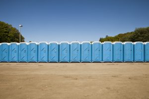 Line of porta potties in a dirt lot